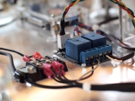 An Arduino brain sends a 5V signal to a 2 relay switches to toggle on/off power to the LEDs and stepper motor driver.